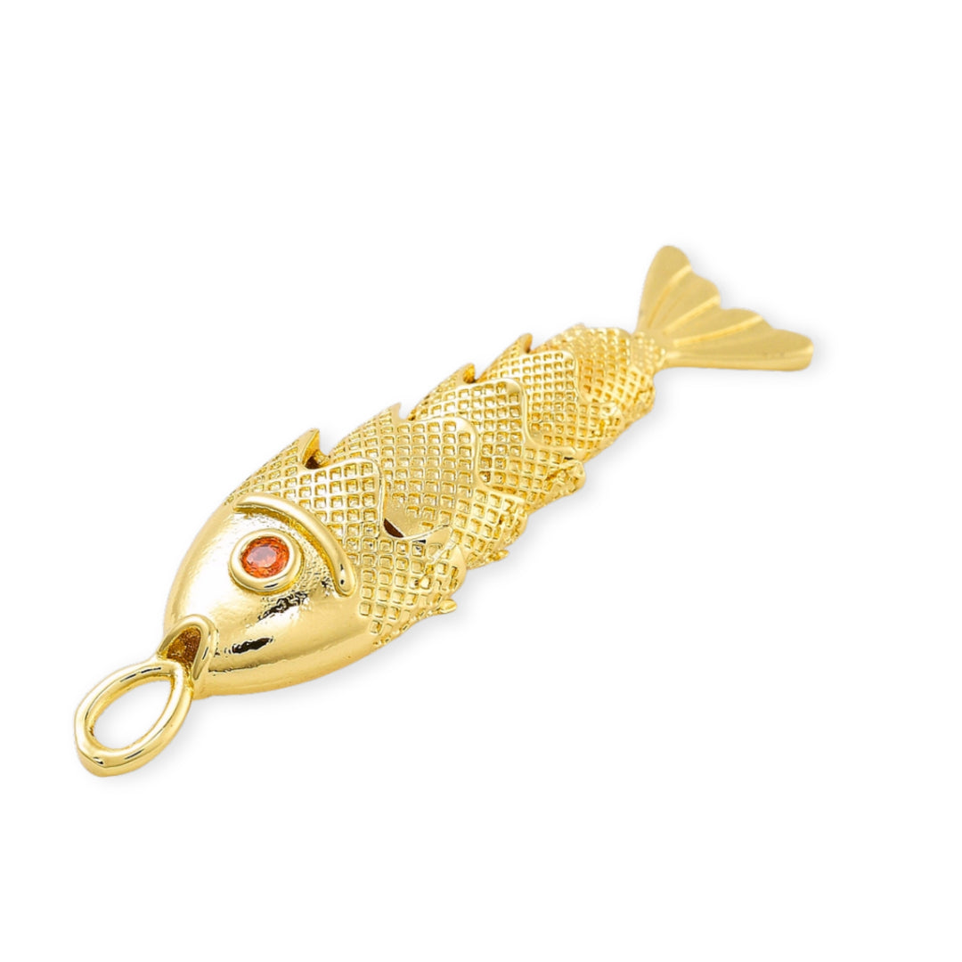 Detalles de Dije dorado en forma de pescado con zirconia roja en el ojo y cuerpo articulado sobre fondo blanco