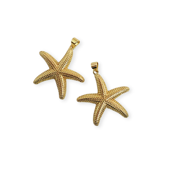 Detalle de dijes dorados en forma de estrella de mar sobre fondo blanco