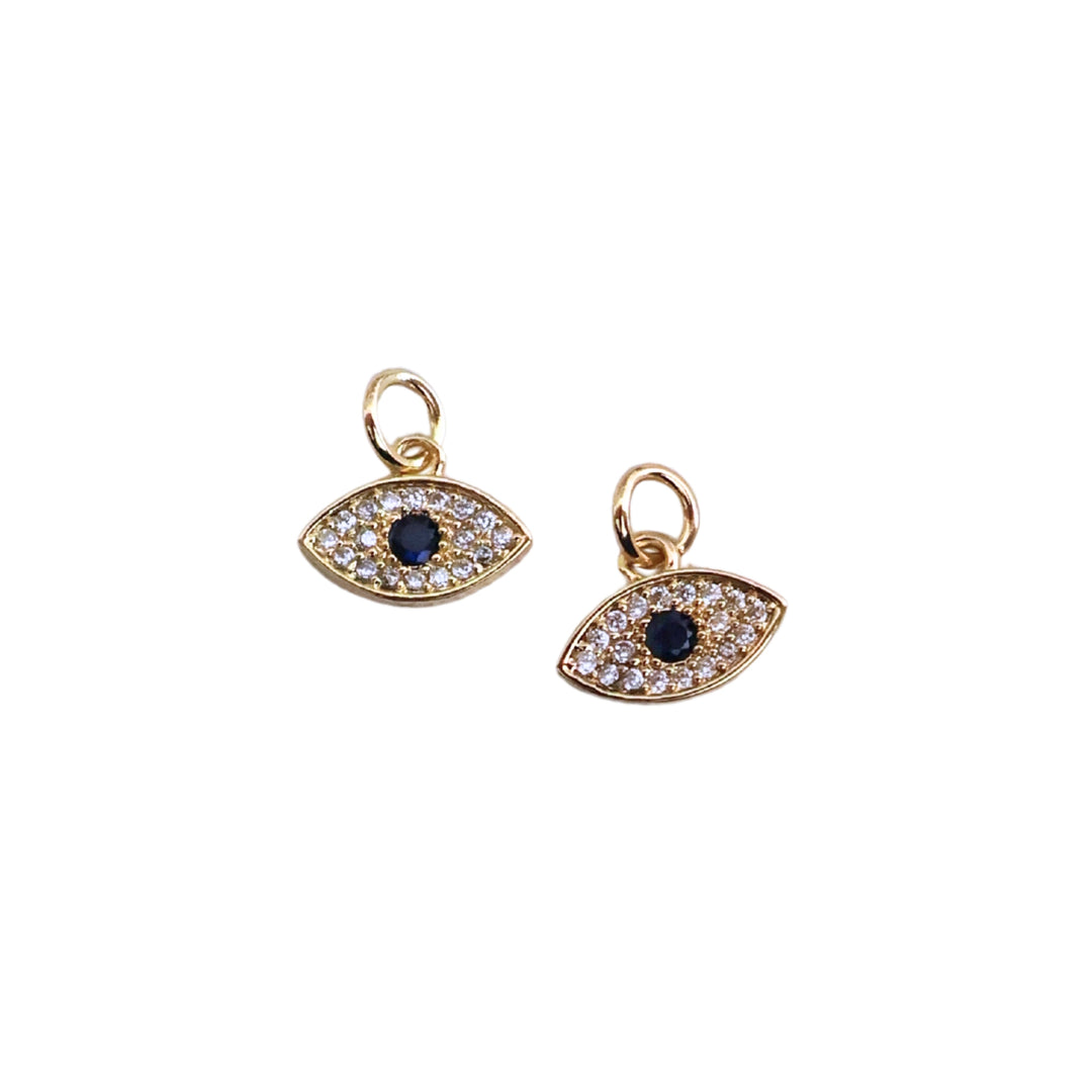 Detalles de dije en forma de ojo dorado en chapa de oro con zirconia al centro