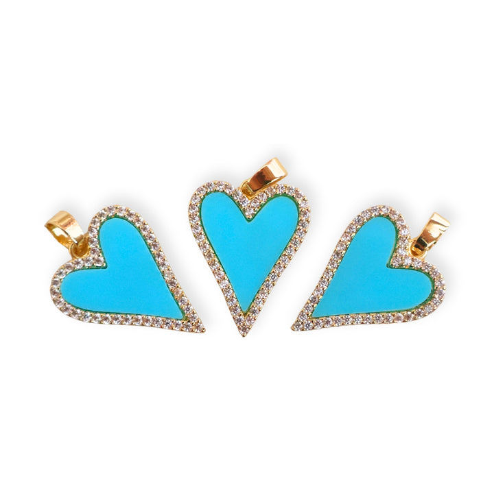 Toma de varios dijes de corazón de chapa de oro con borde de zirconias y esmalte azul sobre fondo blanco