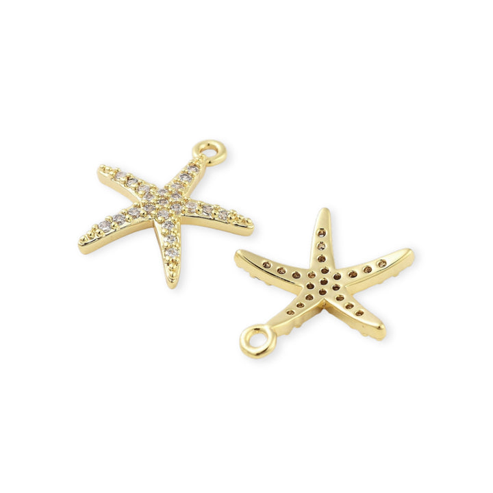Detalles de Dije estrella de mar en chapa de oro con zirconias alrededor sobre fondo blanco