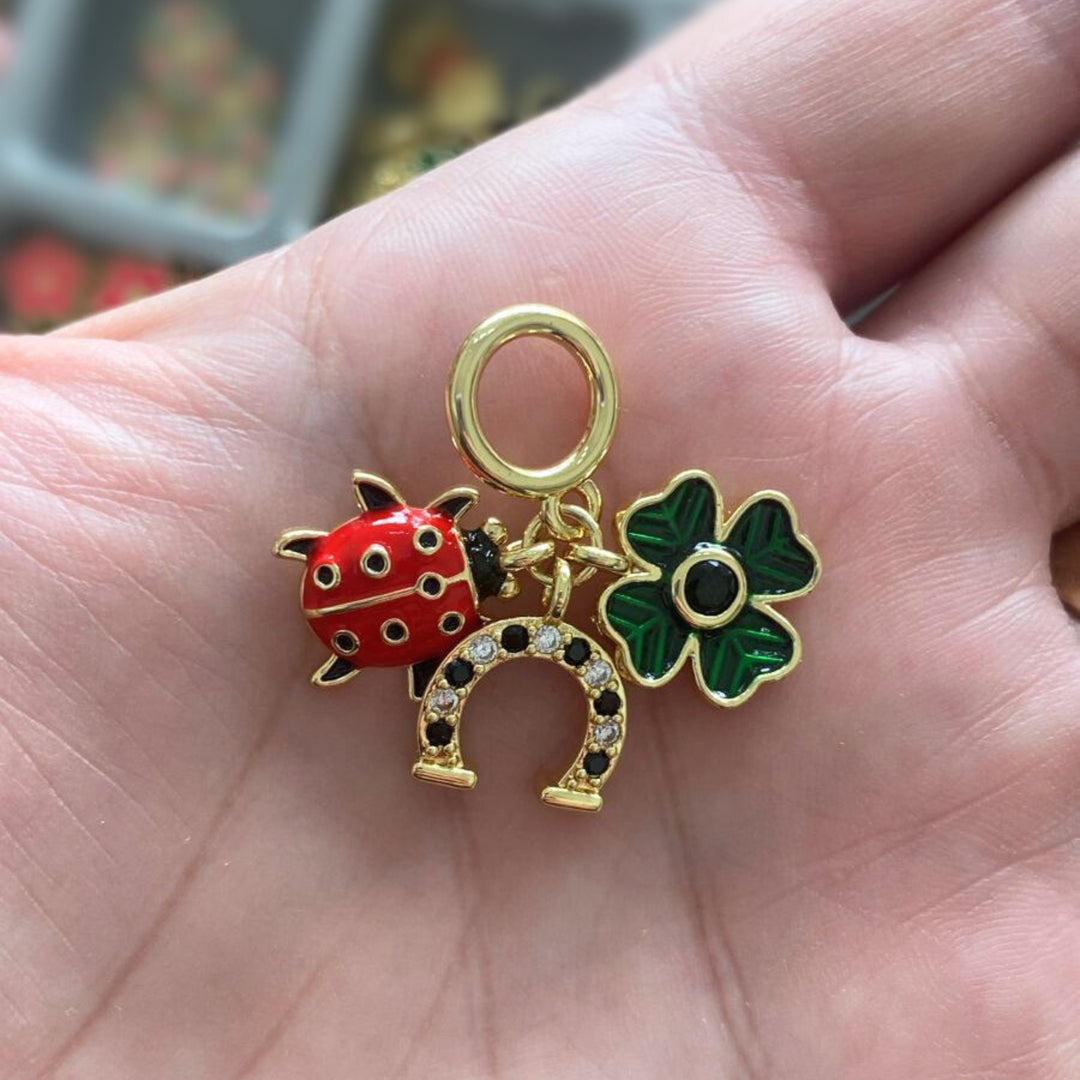 Dije multicharm de catarina, herradura y trébol de chapa de oro en mano