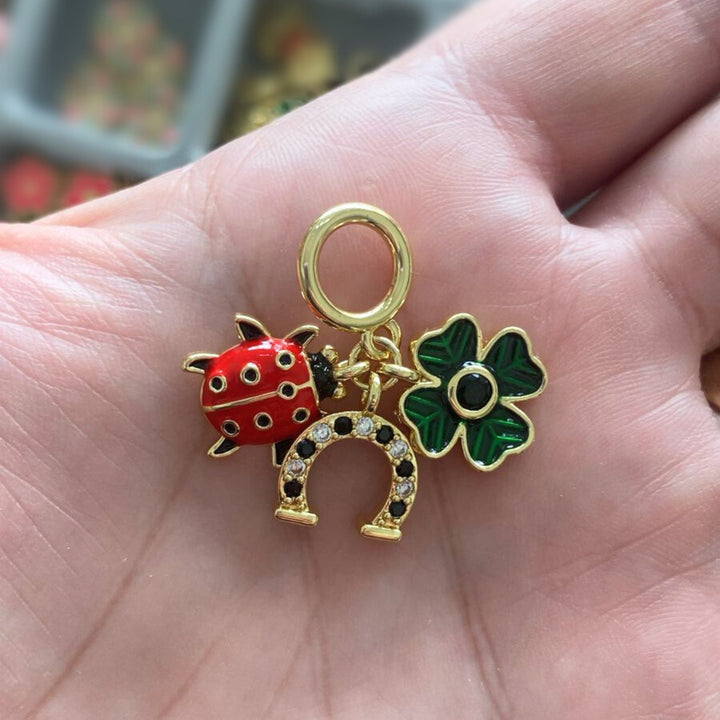 Dije multicharm de catarina, herradura y trébol de chapa de oro en mano