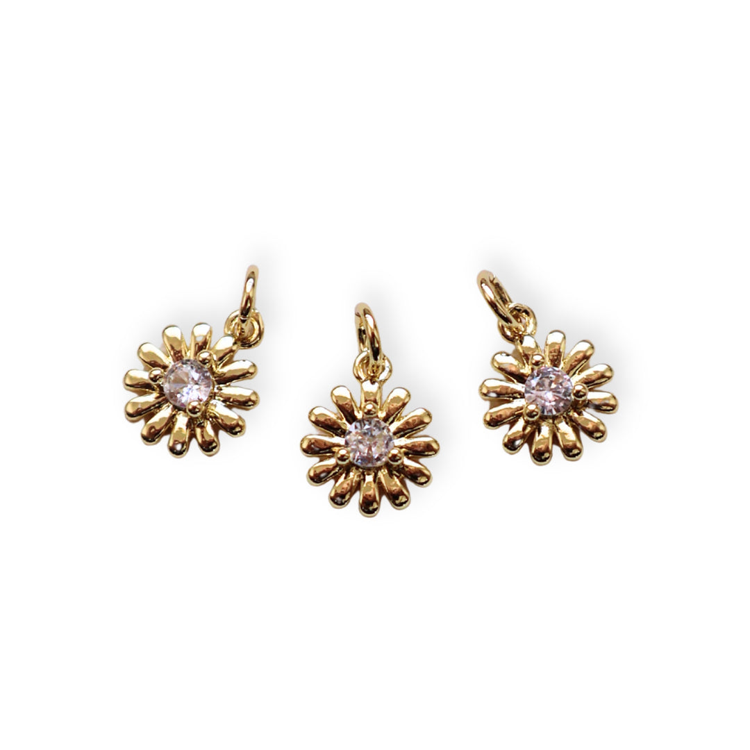 Detalles de dije dorado en forma de flor con zirconia brillante al centro