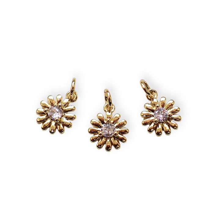 Detalles de dije dorado en forma de flor con zirconia brillante al centro