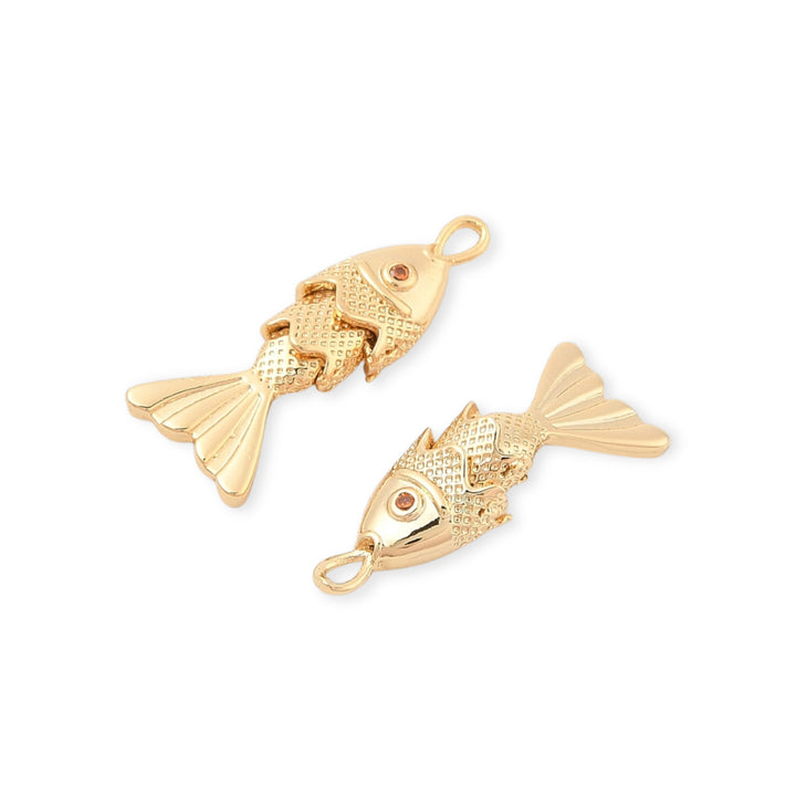 Detalles de Dije dorado en forma de pez con zirconia y aleta móvil sobre fondo blanco