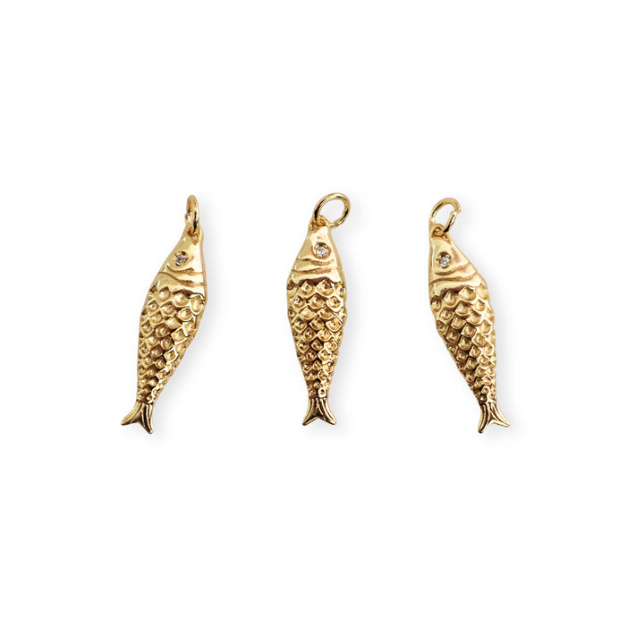 Detalle de dijes de pescado dorado con zirconia en el ojo sobre fondo blanco