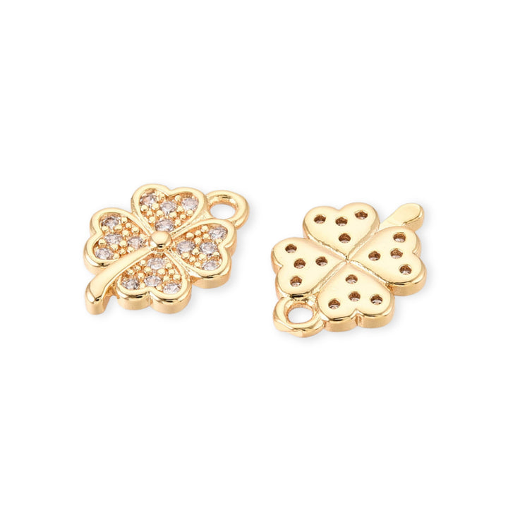 Detalles de Dije dorado en forma de trébol con zirconia al centro sobre fondo claro