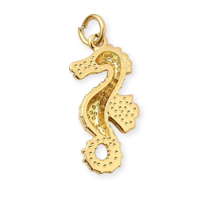 Detalles de Dije dorado en forma de caballito de mar sobre fondo blanco