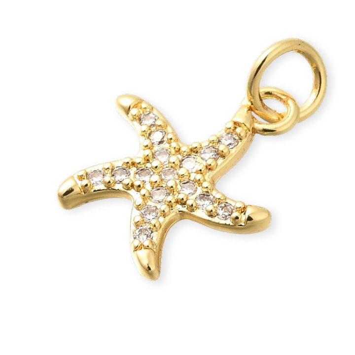 Detalles de Dije de estrella de mar en chapa de oro con zirconias alrededor sobre fondo blanco