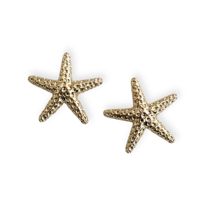 Detalles de dije estrella de mar dorada en chapa de oro sobre fondo blanco