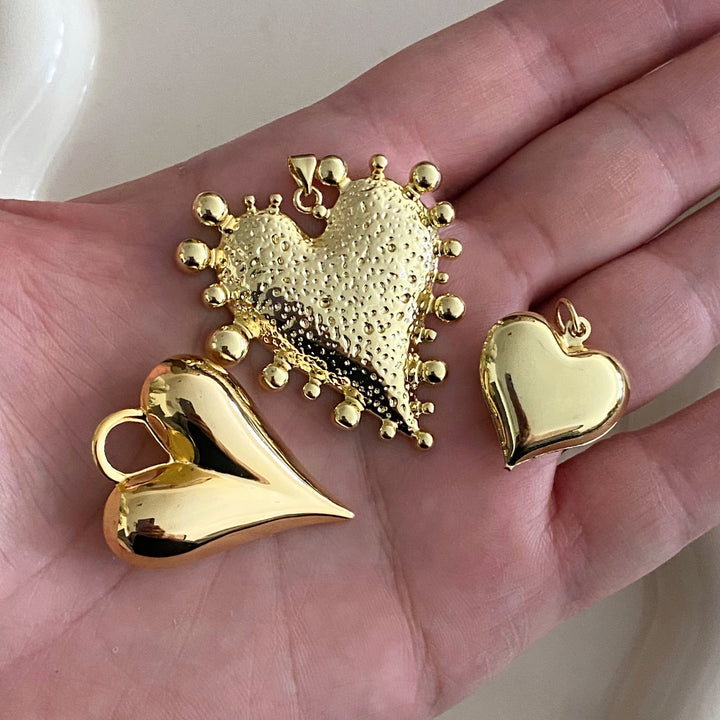 Dije de corazón de chapa de oro en mano