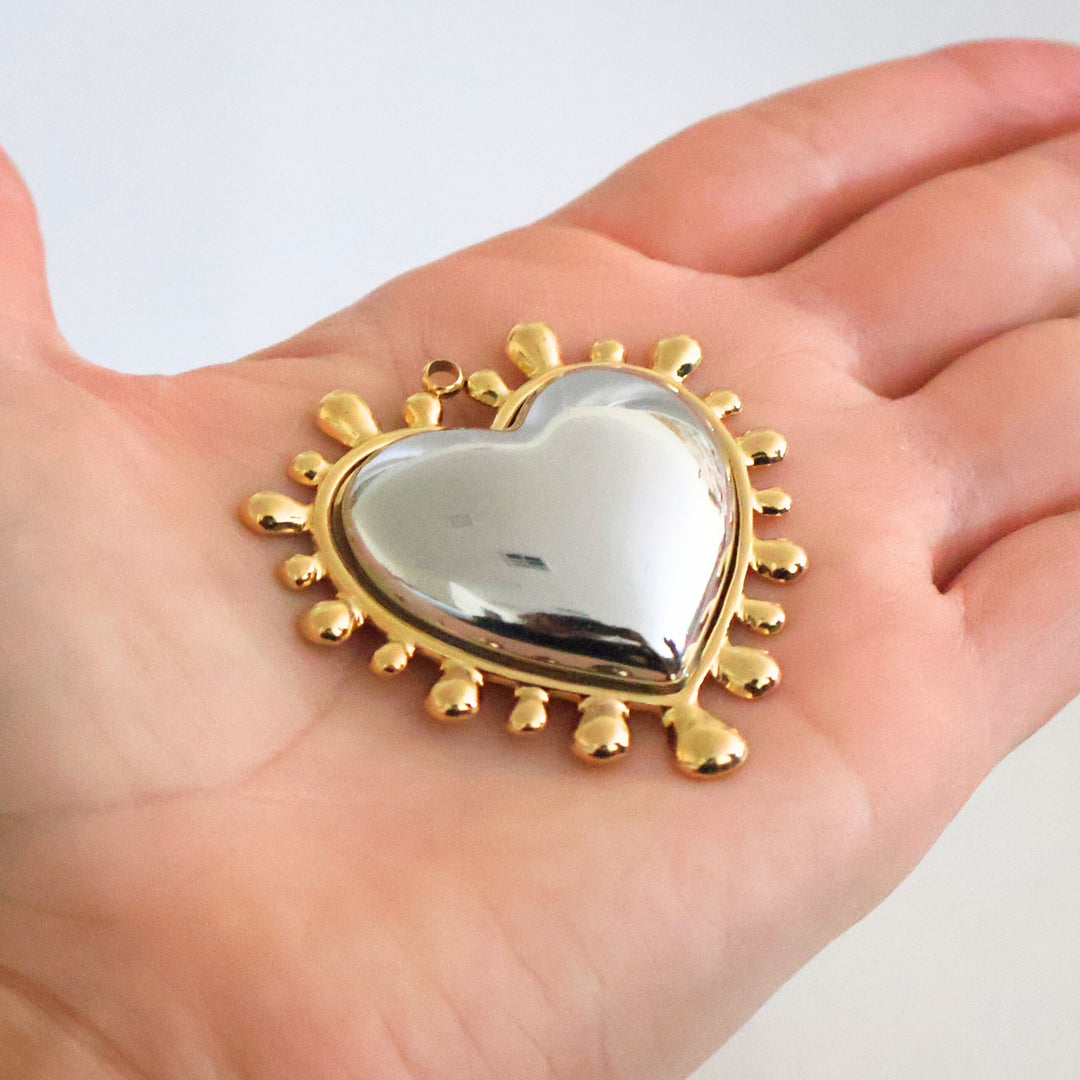 Dije de corazón de acero inoxidable grande en mano