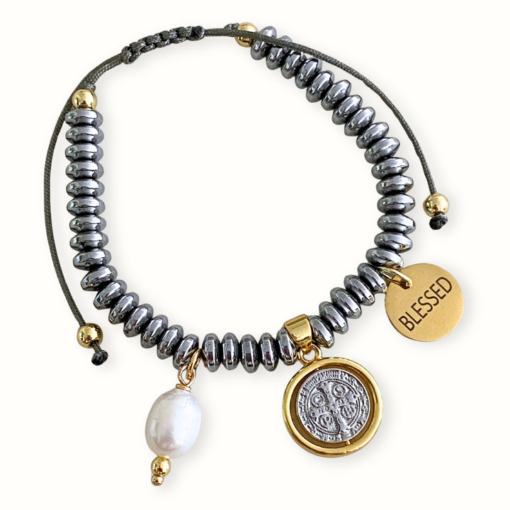 Pulsera ajustable tejida con hilo chino, cuentas de hematita, dije central de San Benito de chapa de oro y platino