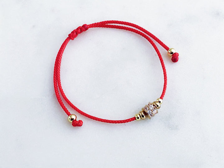 Pulsera de hilo rojo ajustable con separador de zirconias en vista completa.