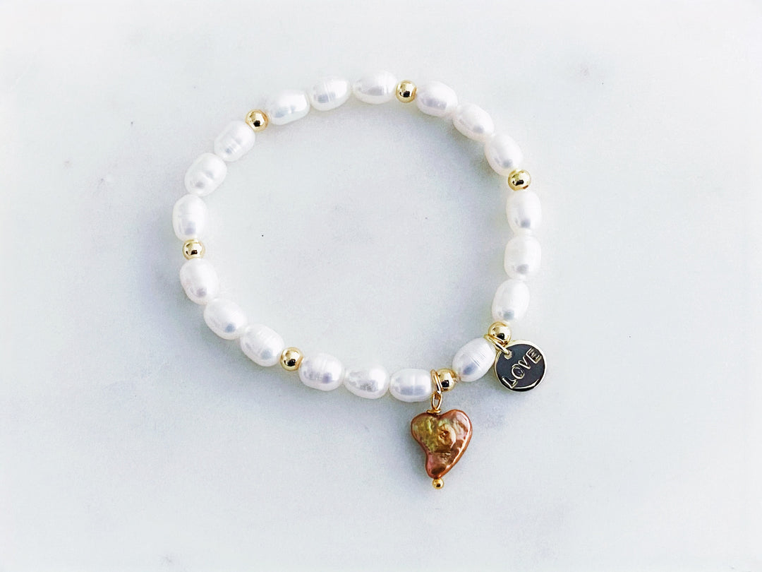 Pulsera de perlas de río con dije dorado "love" y corazón de perla, vista completa.