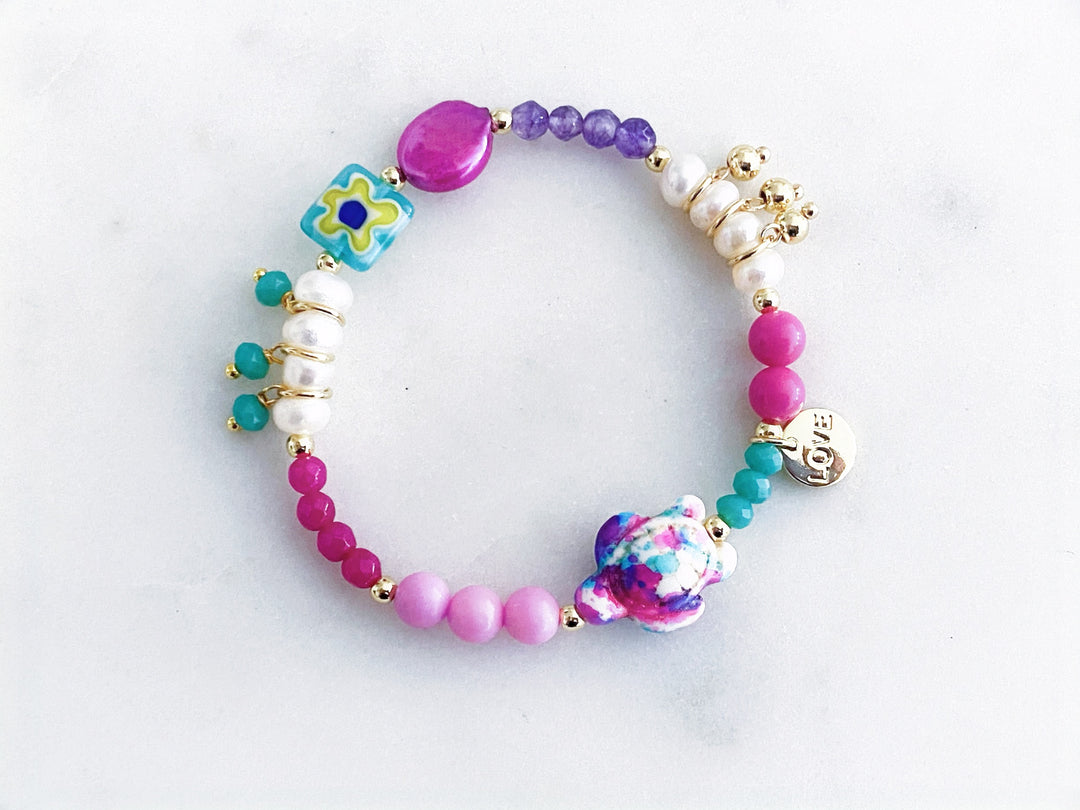 Pulsera multicolor de piedras naturales, perlas y cristales con dije de tortuga y placa “love”, vista completa.