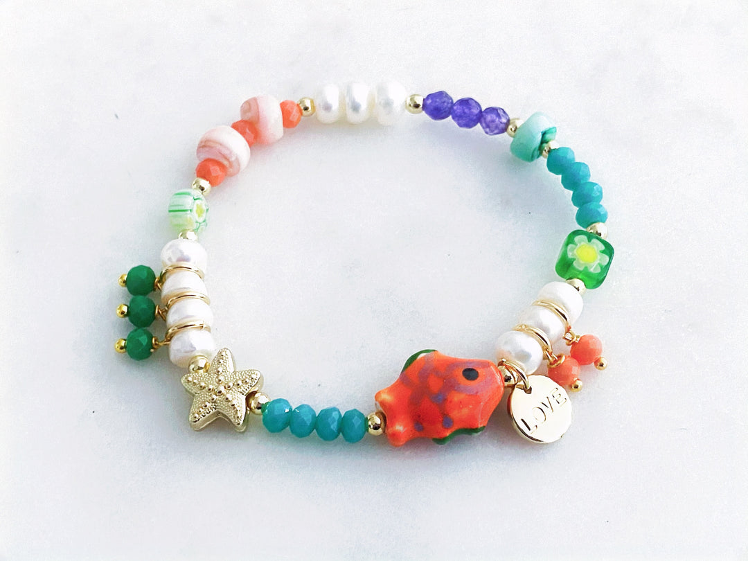 Pulsera con piedras naturales, perlas y cristales con dijes de estrella, pez y “love”, vista completa.