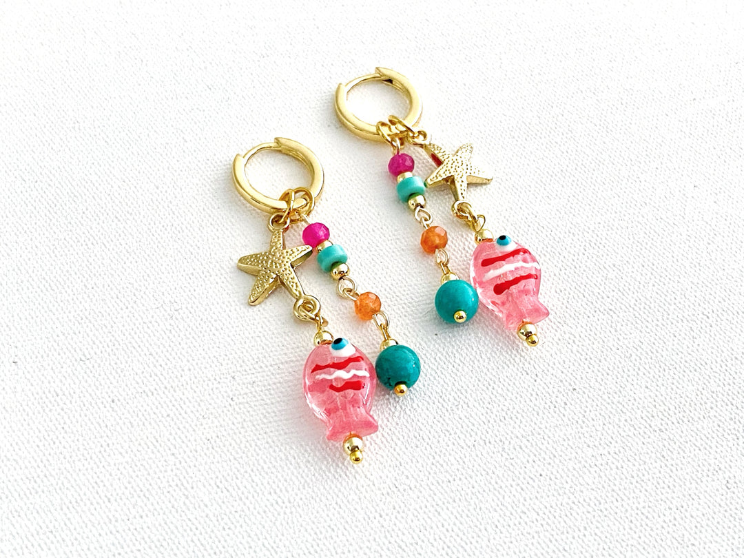 Detalle de piedras en tonos rosa, naranja y azul con estrella dorada y dije de pez