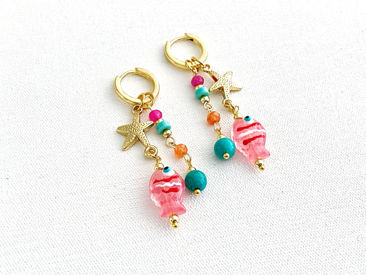 Detalle de piedras en tonos rosa, naranja y azul con estrella dorada y dije de pez